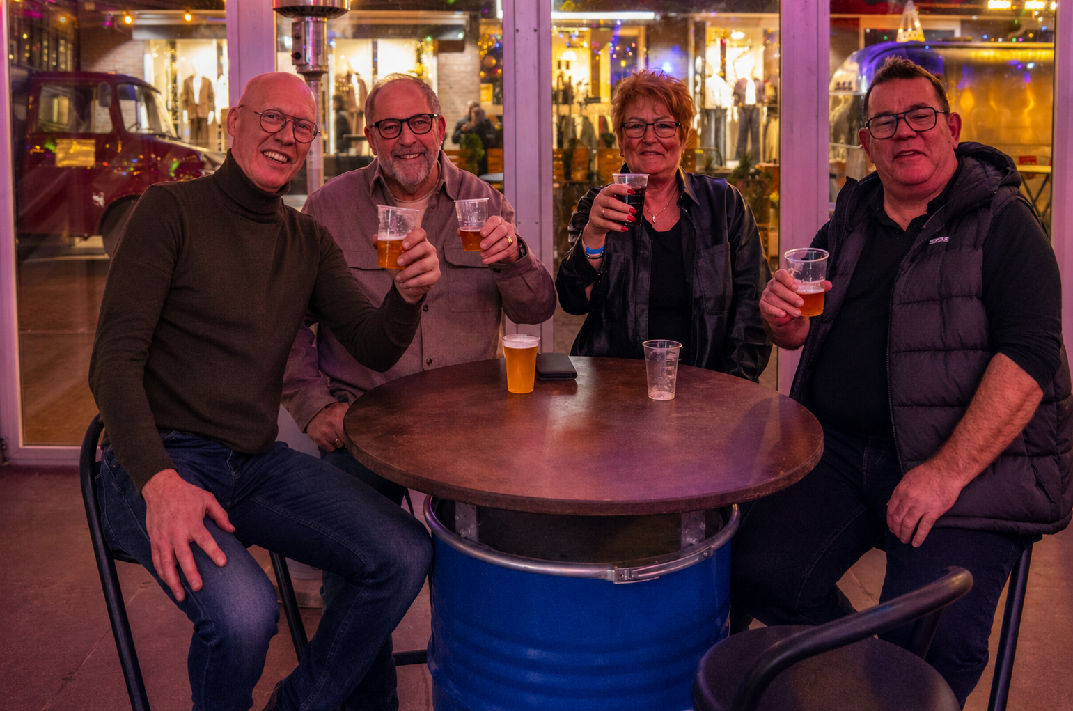 Vier vrienden proosten aan een statafel
